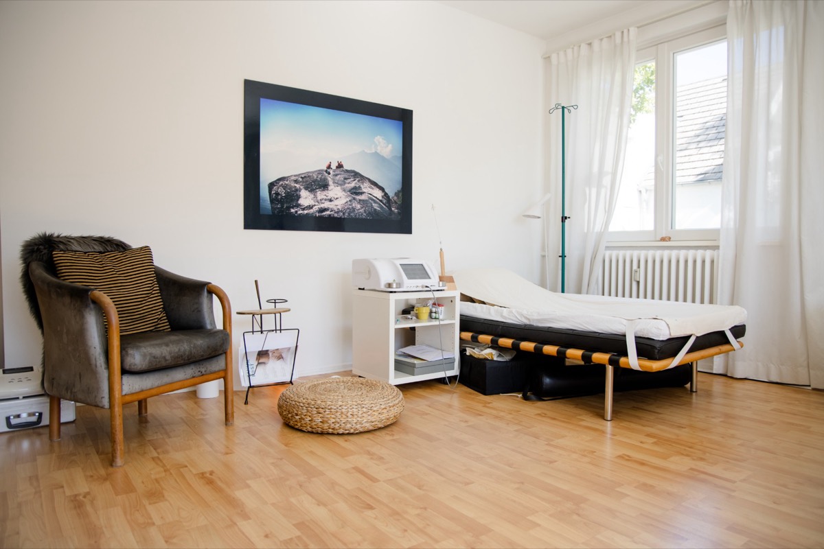 Heller Behandlungsraum mit Sessel, Liege und Tageslicht